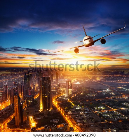 Commercial airplane flying over modern city