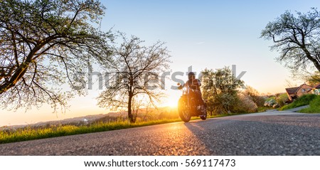 Motorcycle driver driving in beautiful sunset light