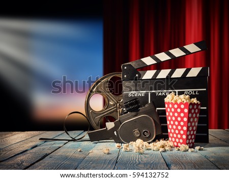 Retro film production accessories placed on wooden planks. Concept of film-making. Red curtain and movie screen on background