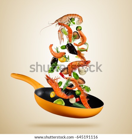 Fresh sea food vegetables flying into a pan, isolated on brown background. Food preparation, fresh meal ready for cooking. Extra high resolution