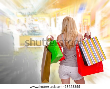 Blond woman with shopping bags in shopping center, back view
