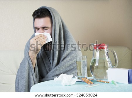 man On Sofa With Medicine And Glass Of Water Man  having flu takes pills, checking fever. flu, colds, fever - seasonal disease