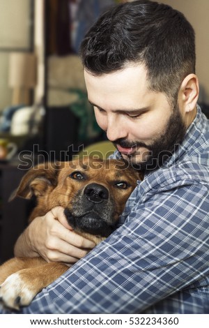 Portrait of a handsome man hugging his lovely crying golden red dog.