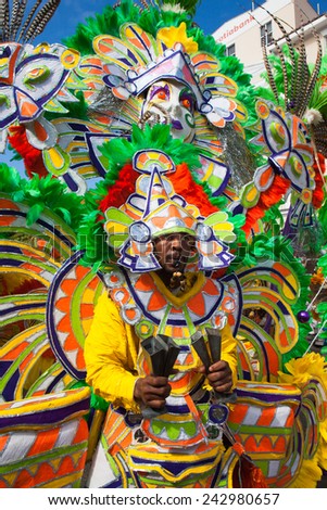 NASSAU, THE BAHAMAS - JANUARY 1 - Whistle blowing dancer dressed in bright orange and green feathers, performs in Junkanoo, a traditional island cultural festival in Nassau, Jan 1, 2011
