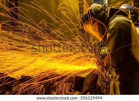 worker in automotive industry movement work grinding parts with sparks