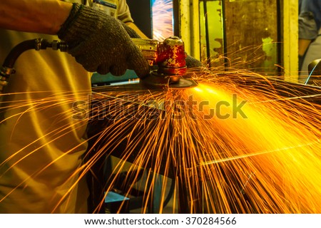 The worker grinding metal in manufacturing plant