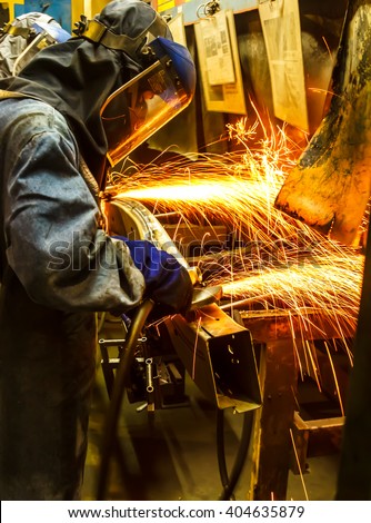The worker grinding metal in manufacturing plant