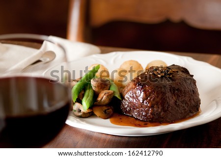 Pepper steak with vegetables and glass of red wine