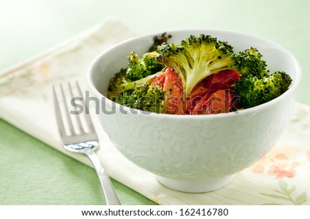 Closeup of a bowl of freshly roasted broccoli and tomatoes.