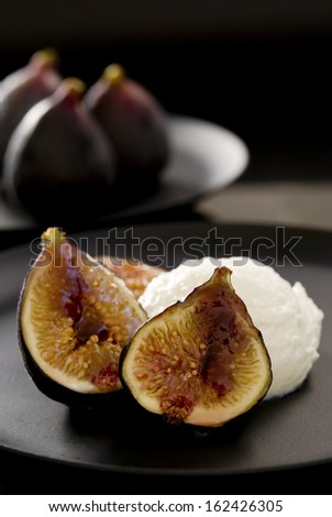Caramelized figs with goat cheese mousse and blackberry sauce on black.