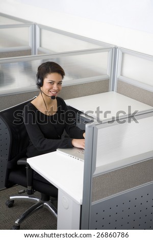 Businesswoman talking on headset in cubicle