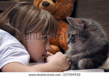 Girl and a cat watching each other\'s eyes. Lovely and good picture. A child and a cat. The relationship of the child with a pet cat