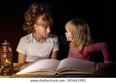 Two sisters tell each other scary stories at night. Open book, vintage lamp (kerosene). Black background. A family. Girls sister, older and one younger. Babies interesting and scary. Bedtime Story