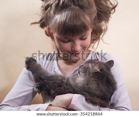 Portrait of a girl with a cat. Young, beautiful girl hugging cat. Cat likes to caress the cat likes to lie in the hands of man. Cat gray, fluffy.  The girl has a beautiful face and hair