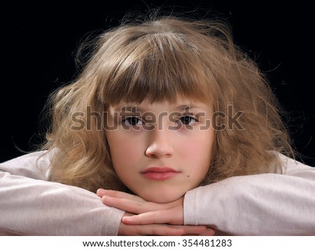Portrait of a young girl. Face close. She put her head in her hands. The eyes are dark brown, handsome face. Teenager. black Background