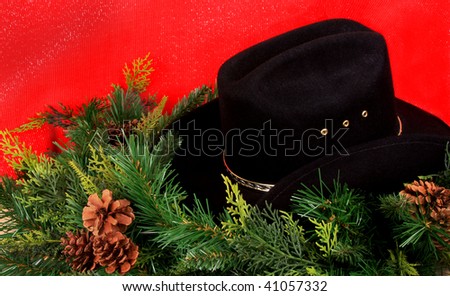 Black cowboy hat and Christmas wreath on red background