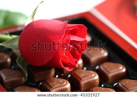 box of assorted chocolates and rose on white background
