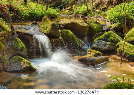 The river runs over boulders in the primeval forest - HDR