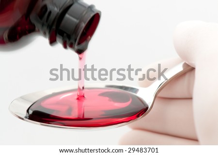 Spoonful of cough syrup being filled by person wearing latex gloves, on white background