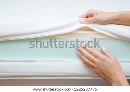 Woman\'s hands touching different layers of new mattress. Checking hardness and softness. Choice of the best type and quality. Front view. Close up.