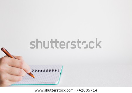 Man\'s hand with pen writing something in the notebook on the table. Education concept. Empty place for a important ideas, plans, memories, messages, to do lists or other text.