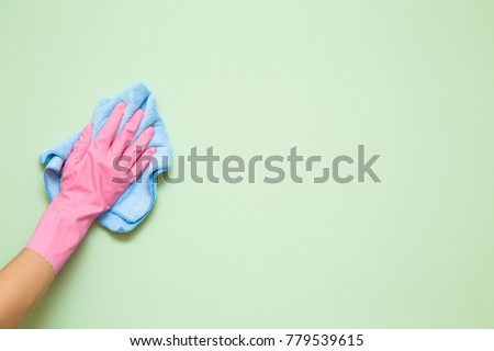 Employee hand in rubber protective glove with micro fiber cloth wiping wall from dust. Maid or housewife cares about house. Spring general or regular clean up. Commercial cleaning company concept.
