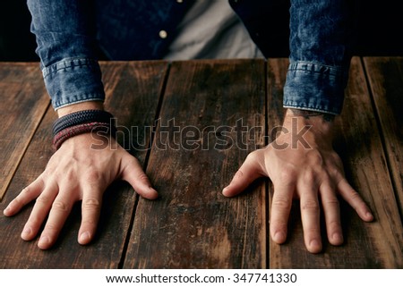 Beautiful men hands on table, jeans casual shirt, tattoo, wrist band, bracelets