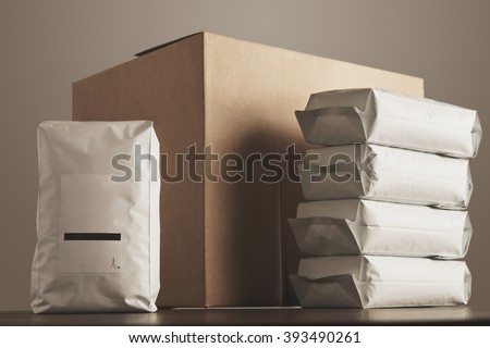 Big blank bulky sealed package with product presented in front of carton craft box and column of other packages. Ready for shipping, delivery and sale. Small business artisan concept.