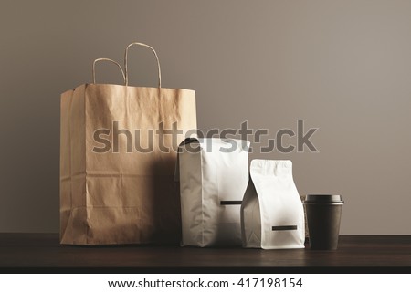 Presentation of retailer package set: craft paper bag, big pouch, small container and take away glass with cap. Filled with goods, blank labeled, merchandise pack