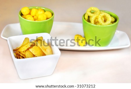 chips and salty snacks in  white and green dishes