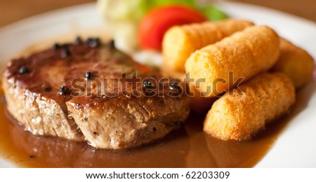 pepper steak with salad, pepper sauce and potato croquettes