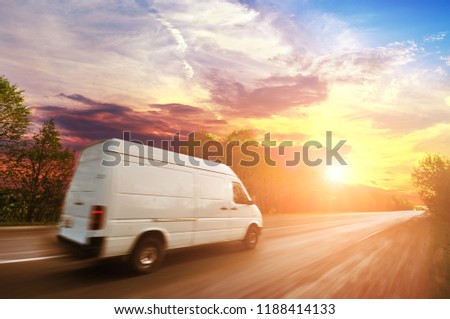 Big white van in motion on the countryside road shipping goods against night sky with sunset