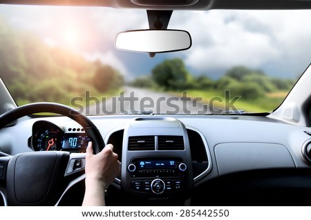 Driver\'s hands on the steering wheel inside of a car