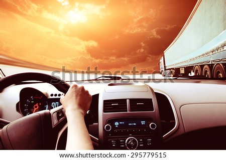 Driver\'s hands on a steering wheel of a car and blue sky with clouds