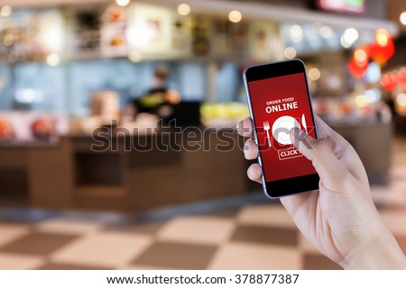 Hand holding smart phone with food order screen on blur of restaurant background