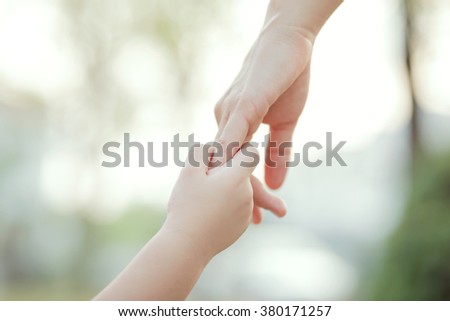 Parent holds the hand of a little child, soft focus, warm tone