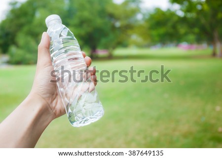 Hand holding fresh water bottle in the park
