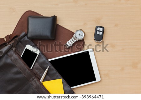 Flat lay of businessman bag with tablet, smartphone, wallet, watch and car remote on table, top view