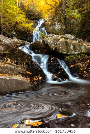 Long exposure waterfall shot, swirling leaves formation in the foreground and distant and close fall colors