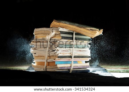 antique stack of books and notebooks with an expanding dust