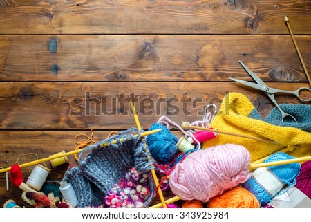 view to a wooden table with lots of balls of wool, knitting needles and other tools.  Place for text