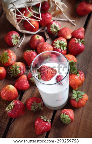 strawberries on a wooden table and a glass with whipped cream and strawberries