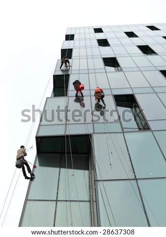 People wash windows of office building