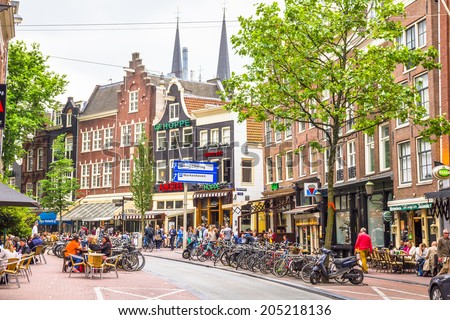 AMSTERDAM, NETHERLANDS - MAY 31, 2014: People drinking on the streets of Amsterdam. Most cafes have terraces in summertime and are full of people enjoying the weather and drinks.