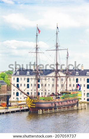 AMSTERDAM, THE NETHERLANDS - MAY 31, 2014: View of a rebuilt Indiaman ship and the Maritime museum in the Amsterdam Harbour. Actors play historic roles on board of the 17th Century ship.