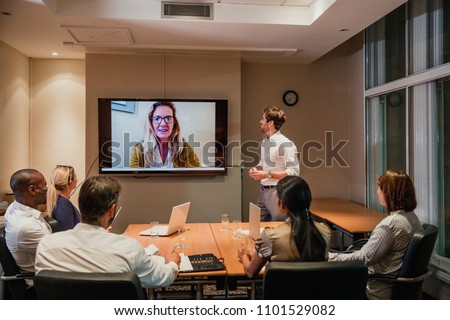 Group of business people having a late night video conference meeting. Sitting around a conference table talking and networking.