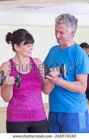 Senior man and woman using weights together at the gym
