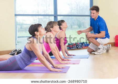 Three women stretching at the gym with the guidance of a fitness instructor