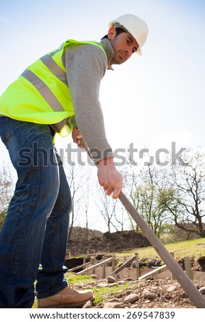 Male construction worker clearing the ground using gardening equipment