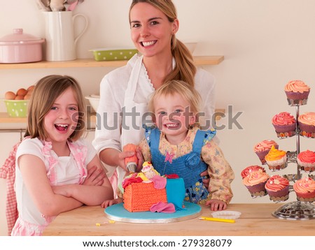 Mother decorating cakes with her two daughters
